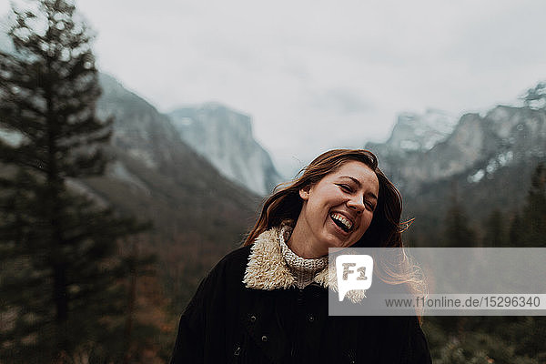 Junge Frau lacht in Berglandschaft  Kopf und Schultern  Yosemite Village  Kalifornien  USA