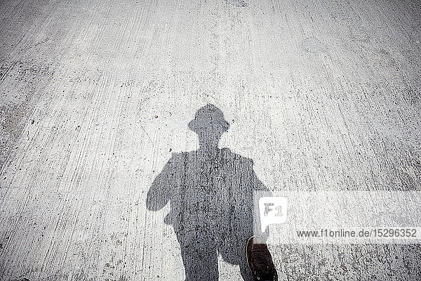 Schatten eines Bauarbeiters auf grauer Betonplatte  persönliche Perspektive