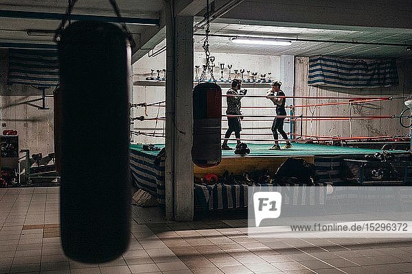 Boxer sparring with trainer in boxing ring