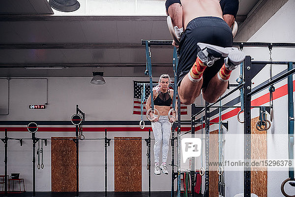 Young couple balancing on gymnastic rings in gym