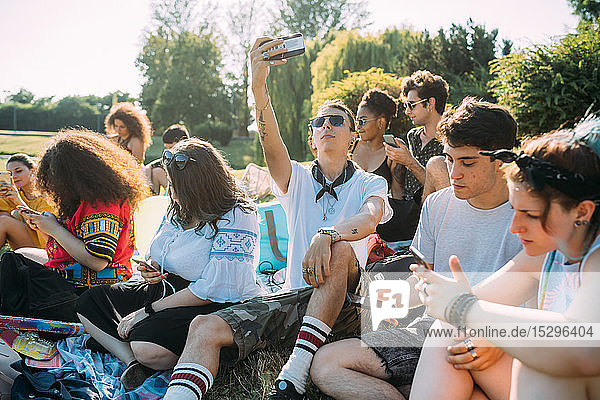 Eine Gruppe von Freunden entspannt sich mit einem Smartphone im Park