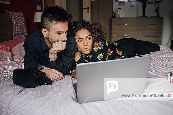 Ehepaar mit Laptop auf dem Bett