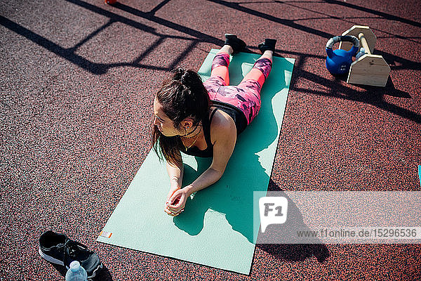 Calisthenics-Kurs im Fitnessstudio im Freien  junge Frau macht eine Pause auf der Yogamatte
