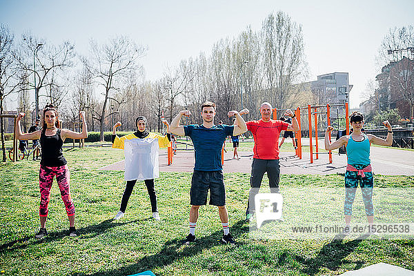 Calisthenics class at outdoor gym  women and men flexing their arm muscles