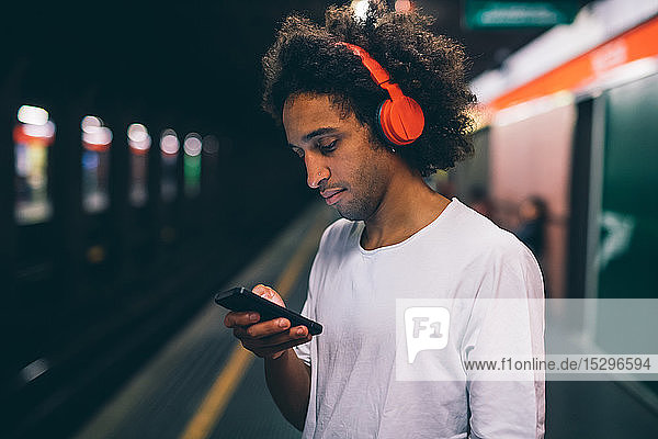 Young man using smartphone on train platform