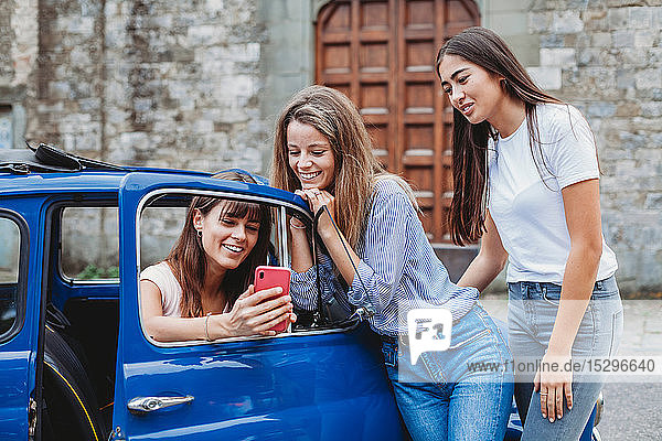 Freunde nutzen Smartphone neben dem Auto