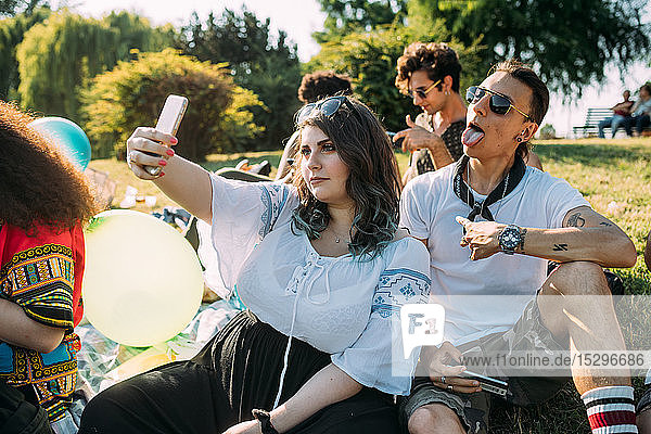 Group of friends relaxing  taking selfie at picnic in park