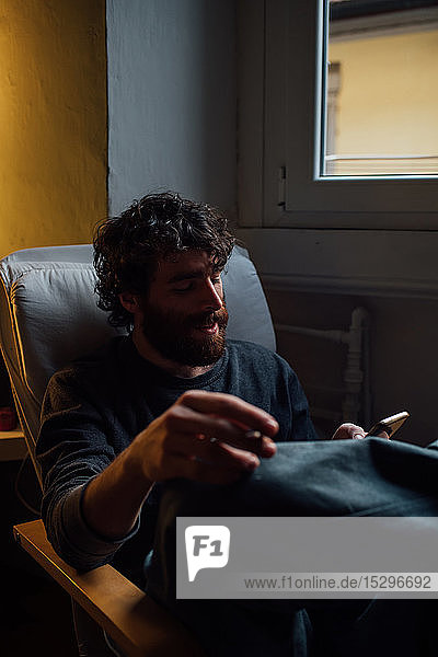 Bearded young man using smartphone at home