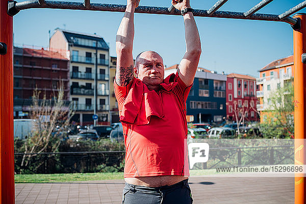 Gymnastik im Fitnessstudio im Freien  reifer Mann beim Hochziehen an Fitnessgeräten