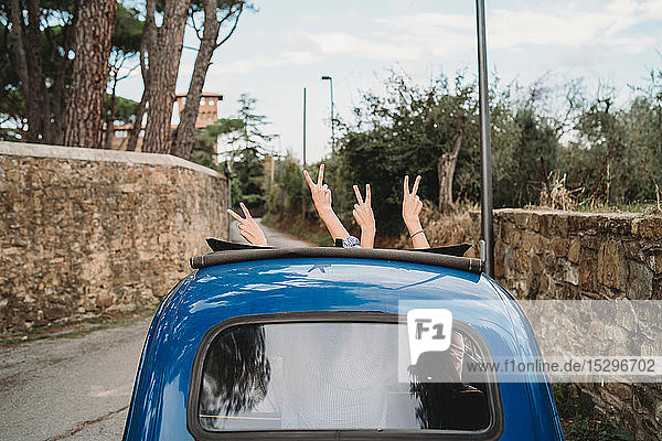 Freunde gestikulieren Friedenszeichen im Autoschiebedach  Florenz  Toskana  Italien