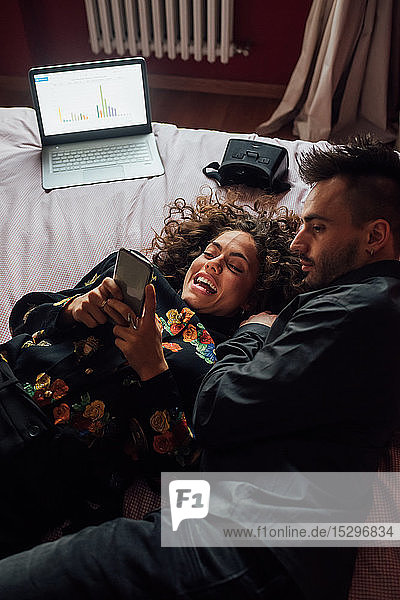 Couple using smartphone on bed
