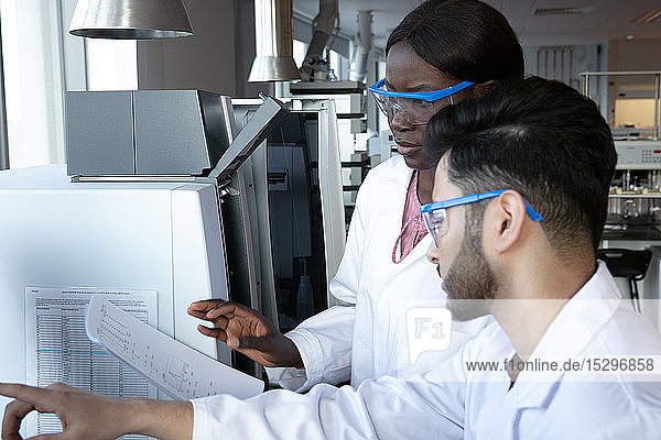 Junge Wissenschaftlerinnen und Wissenschaftler diskutieren im Labor über Papierarbeit