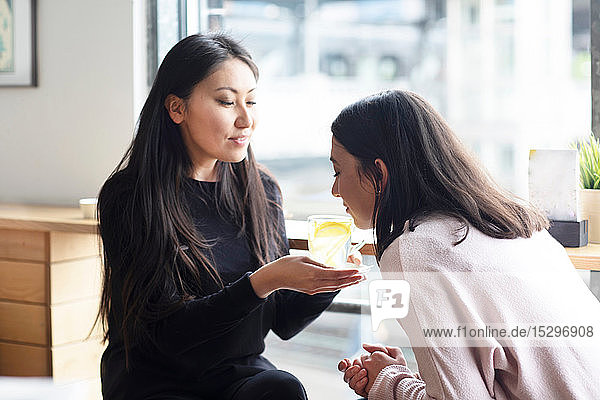 Frau riecht ein Glas Zitronensaft in der Hand eines Freundes