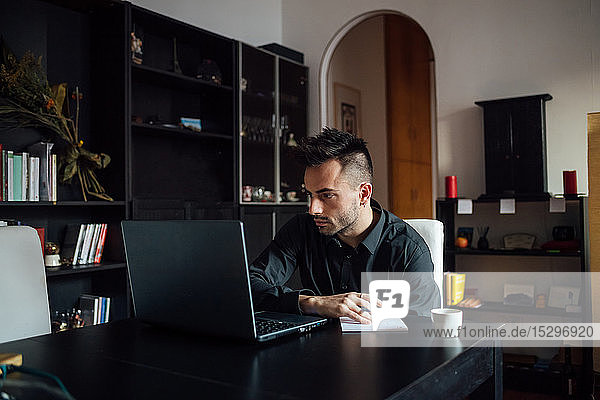 Mann benutzt Laptop im Heimbüro