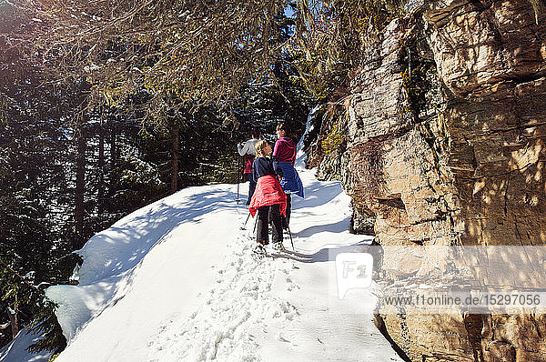 Teenage girl and sisters snowshoeing up snow covered mountainside  Styria  Tyrol  Austria