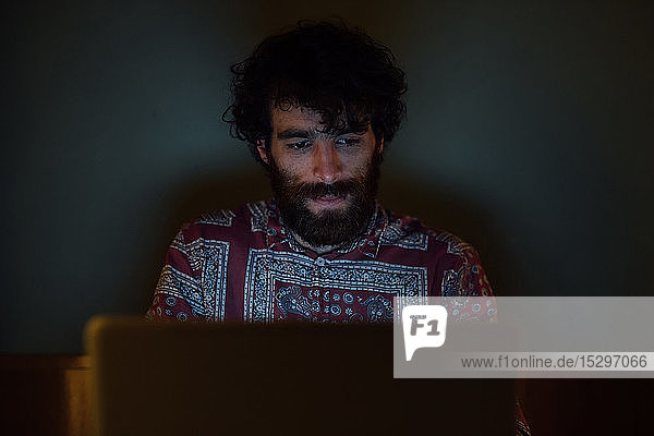 Bärtiger junger Mann benutzt Laptop zu Hause