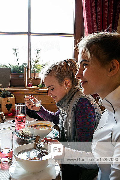 Zwei jugendliche Skifahrerinnen essen in Hütte