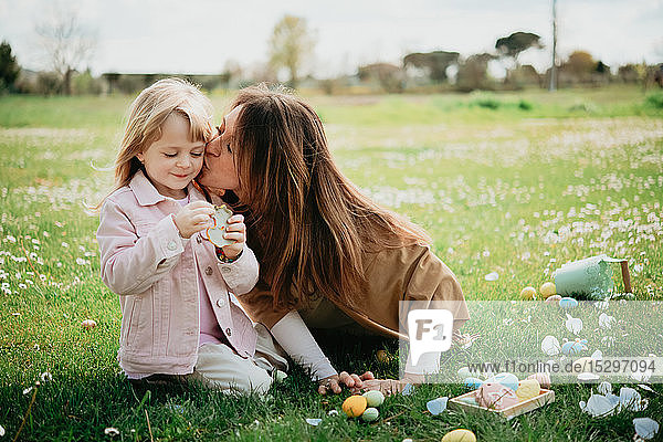 Mutter küsst Tochter im Wildblumenfeld nach der Ostereiersuche  Arezzo  Toskana  Italien