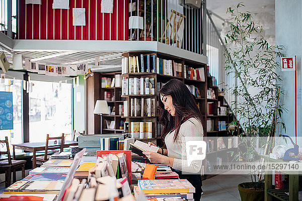 Junge Geschäftsfrau stöbert in Büchern im Buchladen