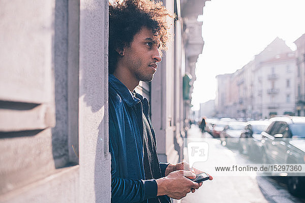 Junger Mann benutzt Smartphone auf Bürgersteig  Mailand  Lombardei  Italien