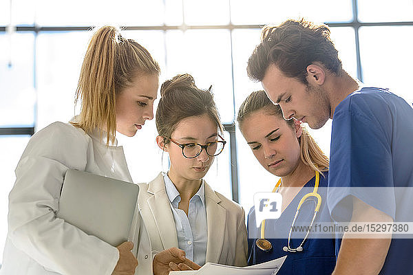 Young female and male junior doctors looking at medical records in hospital
