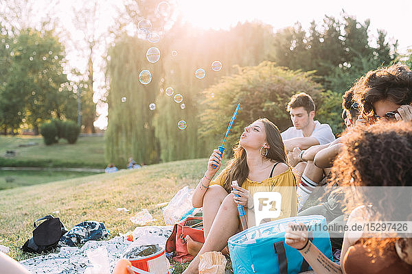 Eine Gruppe von Freunden entspannt sich beim Picknick im Park und bläst Seifenblasen