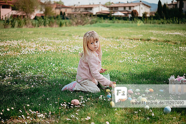 Hübsches Mädchen sitzt im Feld und sammelt Ostereier auf  Porträt  Arezzo  Toskana  Italien