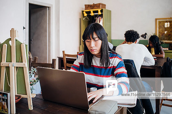 Young businesswoman remote working on laptop at cafe table