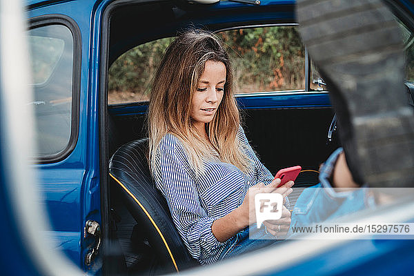 Woman using smartphone inside car