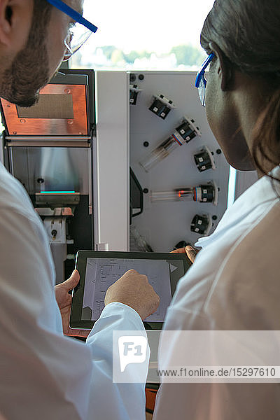 Junge Wissenschaftlerinnen und Wissenschaftler betrachten digitale Tabletts im Labor Blick über die Schulter