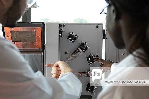 Junge Wissenschaftlerinnen und Wissenschaftler betrachten wissenschaftliche Geräte im Labor Blick über die Schulter