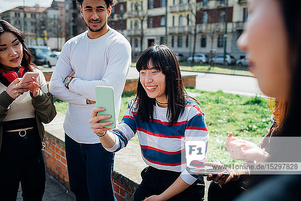 Junge weibliche und männliche erwachsene Freunde nutzen Smartphones in der Nähe der Stadtstraße