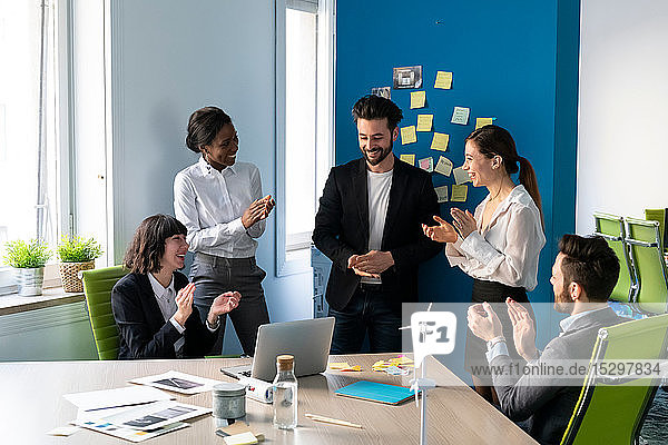 Young male and female business creative team applauding each other in office meeting
