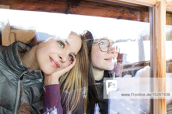 Zwei jugendliche Skifahrerinnen schauen durch das Kabinenfenster hinaus  Tirol  Steiermark  Österreich