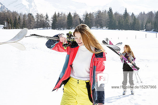 Two teenage girl skiers walking in snow covered landscape  Tyrol  Styria  Austria