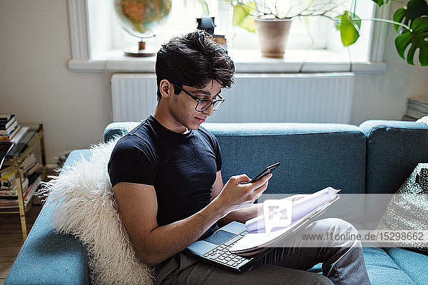 Junger Mann E-Learning beim Sitzen auf dem Sofa im Wohnzimmer zu Hause