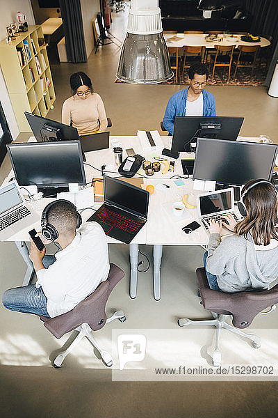 Hochwinkelansicht von männlichen und weiblichen Programmierern  die im Büro am Schreibtisch sitzen