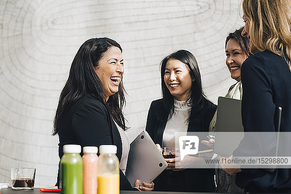 Fröhliche weibliche Fachkräfte vernetzen sich bei Konferenztreffen im Büro