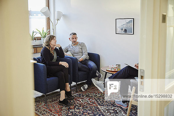 Man and woman talking to counselor while sitting at workshop
