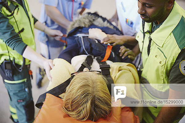 Schrägansicht von medizinischem Personal  das eine Patientin auf einer Krankenhausbahre tröstet