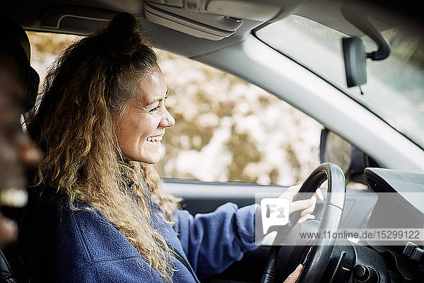 Seitenansicht einer glücklichen jungen Frau beim Autofahren