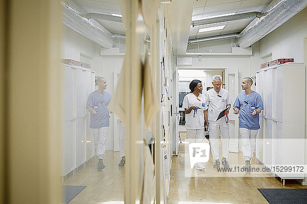 Ärztliches Team diskutiert in voller Länge  während es zusammen auf dem Flur im Krankenhaus geht