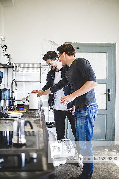 Junge Geschäftsleute kochen Kaffee in der Küche an einem kreativen Arbeitsplatz