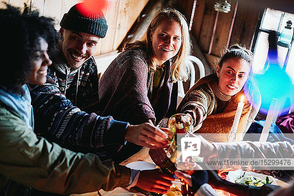 High angle view of happy male and friends toasting drinks in log cabin