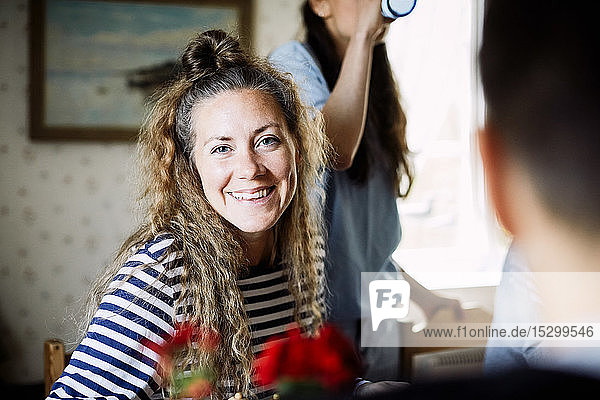 Portrait of smiling female enjoying social gathering with friends at home