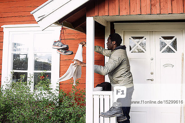 Side view of young man drying clothes while standing outside cottage