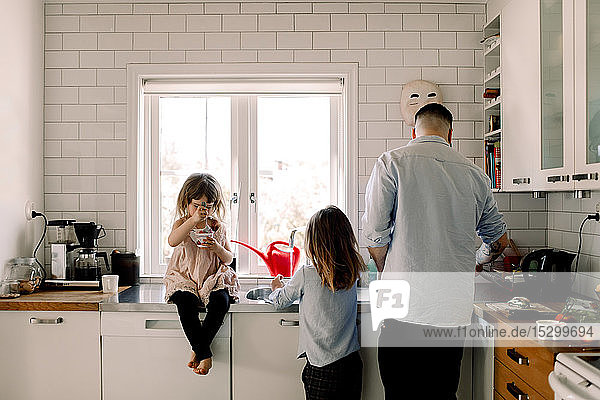 Vater und Tochter arbeiten  während das Mädchen zu Hause in der Küche isst