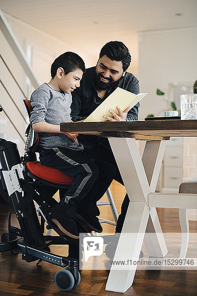 Vater unterrichtet autistischen Sohn  während er im Wohnzimmer am Tisch sitzt