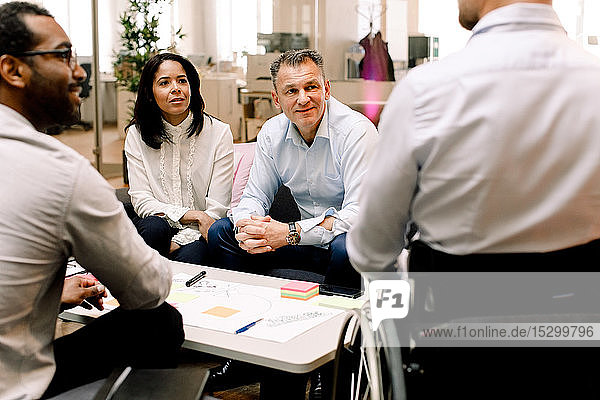 Geschäftskollegen betrachten einen behinderten Vertriebsleiter während einer Besprechung im Büro
