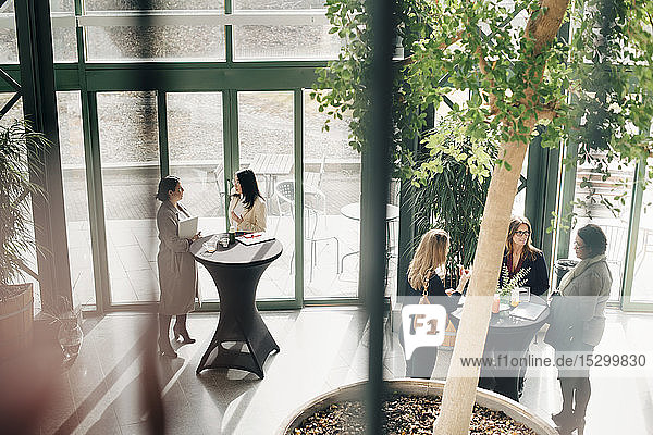 High angle view of female business entrepreneurs discussing at tables in event